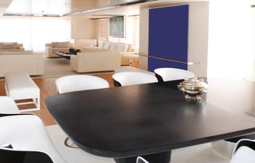 Black dining table and white chairs on the interiors of charter yacht AIR