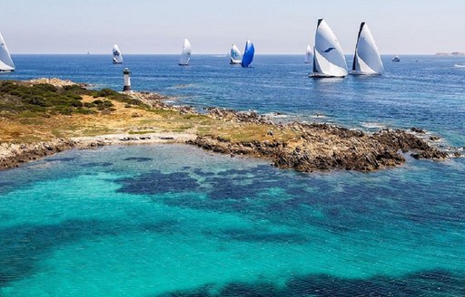 Secluded cove in the Costa Smeralda in Sardinia, with sailing yachts in background