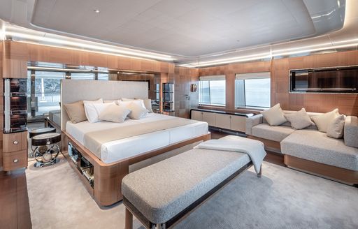 Overview of the master cabin onboard charter yacht SUNRISE with cream upholstery and a central berth with seating underneath a window