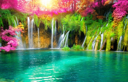 Picturesque waterfalls surrounded by lush green and pink foliage