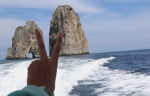 Beyonces hand with oceans and rocks in background from the deck of superyacht KISMET