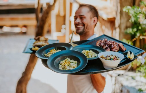 Waiter carrying tray of dishes at Laganini