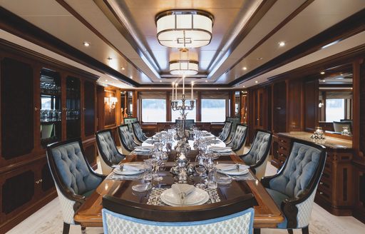 Formal dining room with long table and dark wood onboard superyacht charter TITANIA