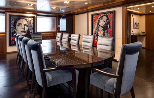 Formal dining table with unusual artwork behind on walls of superyacht RARITY