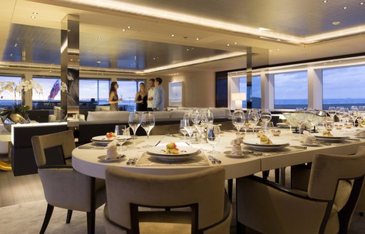 table set for dinner with guests socializing in the lounge on board charter yacht NAUTILUS 