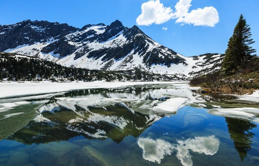 snow covered mountains reflected in the water in Alaska