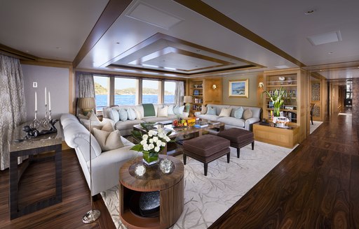 Main salon onboard Charter Yacht 'Lady Britt', U shaped seating around coffee table, with bookshelves and far reaching corridor