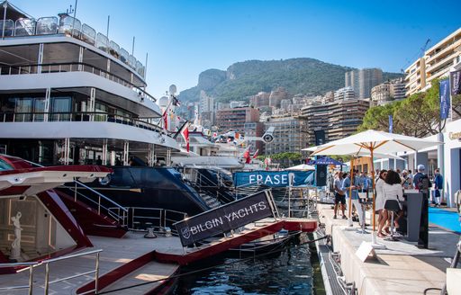 Motor yacht charters berthed at Monaco Yacht Show with exhibitor banners