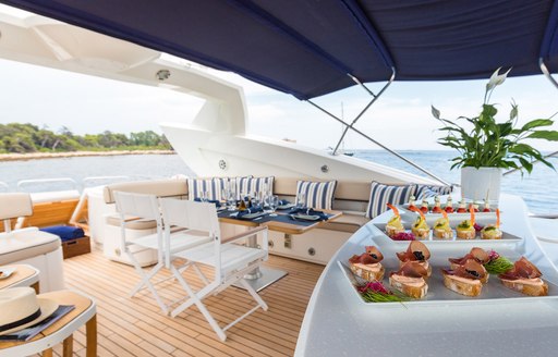 Alfresco dining setup oboard charter yacht Winning Streak 2 with dining table and chairs plus fine cuisine in the foreground