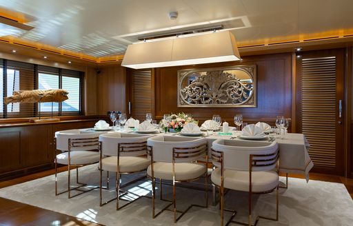 Interior dining area onboard charter yacht LADY I with long table and surrounding white chairs