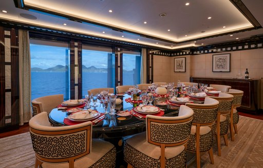 Interior dining area with long table and large windows onboard charter yacht ALFA NERO
