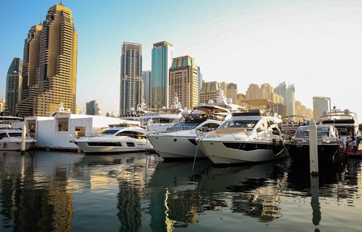 A line-up of superyachts with the Dubai skyline in the background