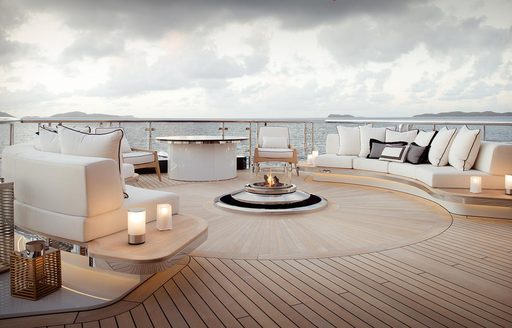 Exterior deck space onboard charter yacht WHISPER with white seating and a central fire pit