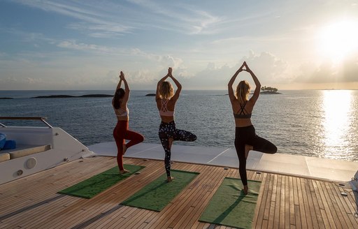 guests on a luxury yacht charter enjoying their vacation by doing some morning yoga to welcome in the sun 