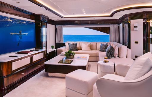 Interior seating area with plush sofas and large window onboard charter yacht IDYLLIC