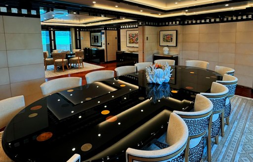 Interior dining area with long black table and surrounding chairs onboard superyacht charter ALFA NERO