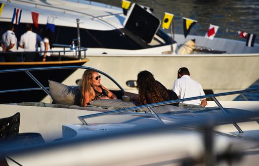 Women recline on sunpads on a yacht while looking out at F1 Monaco Grand Prix