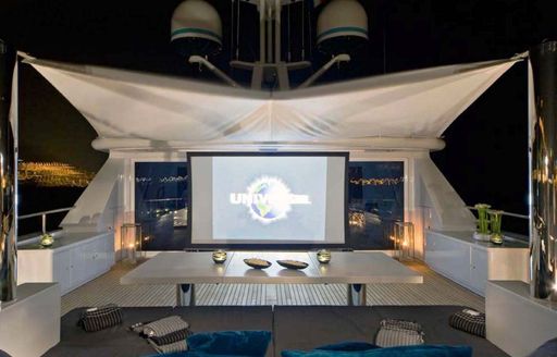 Exterior cinema screen and canopy at night onboard yacht charter CYAN