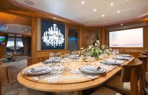 Interior dining area with a large oval table and wooden seats onboard charter yacht BELLA STELLA