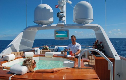 Woman lounging inside a designer jacuzzi while she is being served cocktails by the crew of charter yacht Lady J