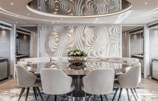 Formal dining area onboard charter yacht SEVERIN'S, circular table surrounded by chairs and large windows to starboard 