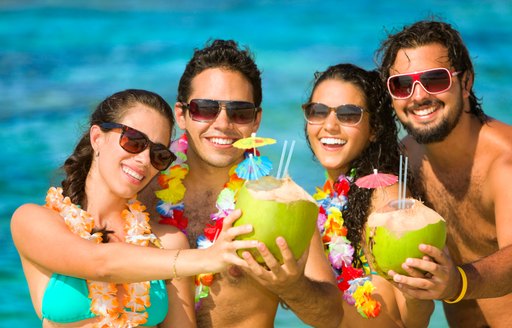 Four young people drink cocktails on a tropical beach