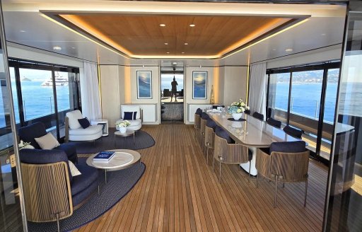 Overview of the upper salon onboard yacht charter AKULA with dining area to starboard and lounge seating port