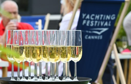 tray of champagne in foreground with deck chair decorated in Cannes Yachting Festival logo