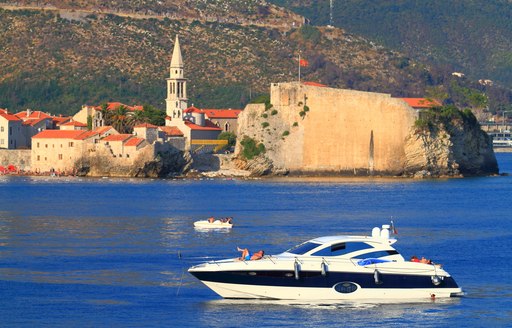 A charter yacht at anchor with large cliffs in the background