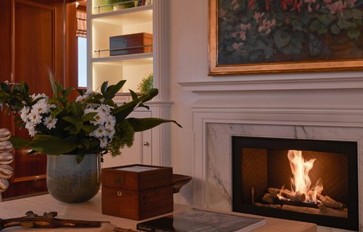 Fire roaring on board a luxury yacht, with painting hanging above and flowers on table