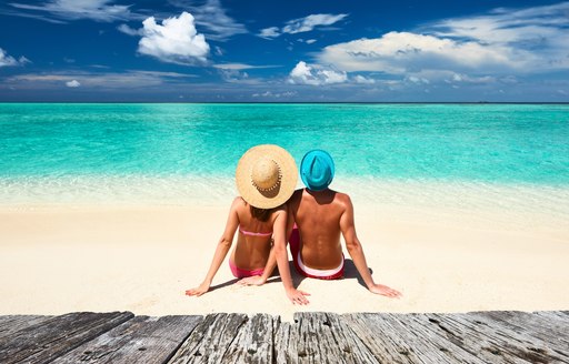 man and woman relax together on a white-sand beach in the Maldives