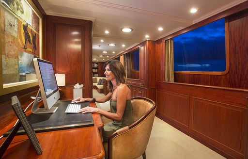 Woman using an imac inside the professional and versatile office of charter yacht Lady J