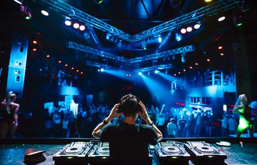 DJ holding headphones in front of mixing decks at Monaco Grand Prix