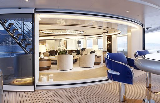 Exterior deck with blue stools at a wet bar and entrance to an interior lounge in the background onboard superyacht charter EXCELLENCE