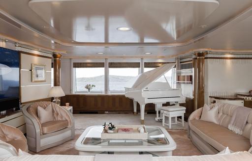 Interior seating area with white piano onboard charter yacht OLYMPUS