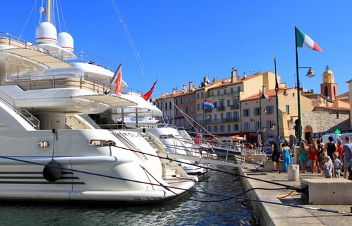 Tourists in the old port of St Tropez, admiring the expensive luxury yachts