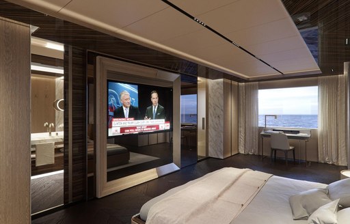 the large flat screen tv inside the master cabin of motor yacht geco with the windows wide open looking outtowards the ocean