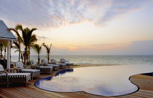 infinity pool on thanda island with sun loungers lined up next to it and sea in background