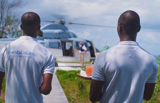 staff wait to give cocktails to guests arriving via helicopter on thanda island