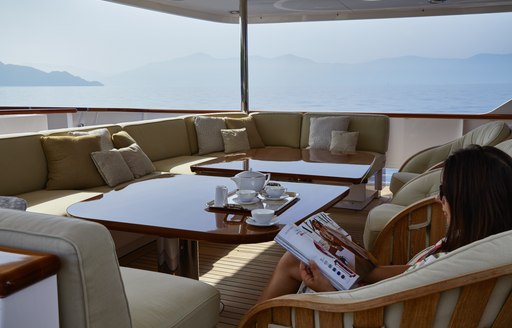 charter guest reads a magazine on the aft deck of charter yacht ANCALLIA 