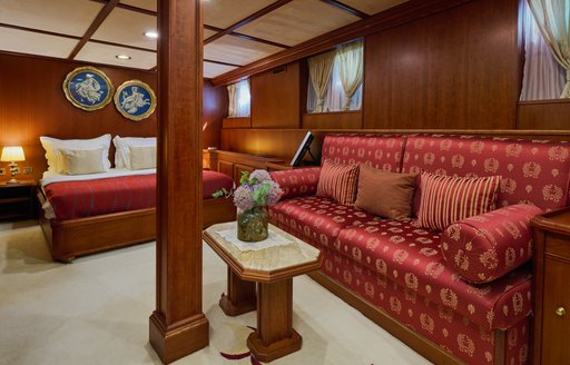 Overview of the master cabin onboard charter yacht SEAGULL II, central berth with a red sofa in the foreground