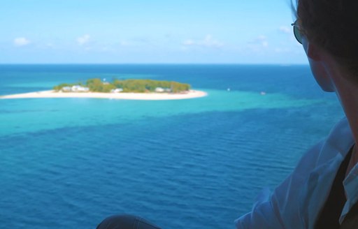 woman looks out at thanda island from helicopter window