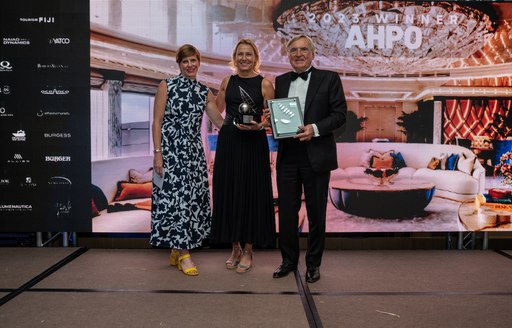 Three AHPO representatives pose with awards in front of seating area at the Ritz-Carlton