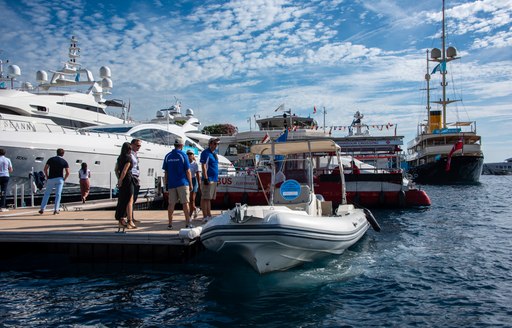 Visitors and crew at the Monaco Yacht Show surrounding a tender by a pontoon