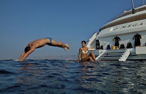 Man dives off the swim deck of O'MEGA while a woman watches