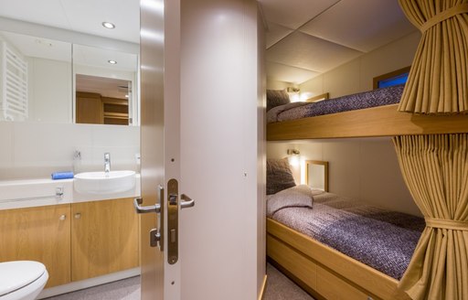 Bunk beds in Game Changer yacht, with door open to bathroom and sink visible