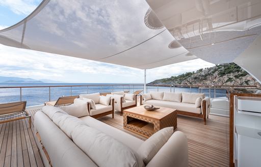 Alfresco lounge area with plush cream seating on the aft deck of charter yacht SUNRISE