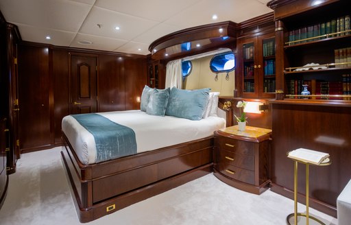 Master cabin onboard charter yacht PURPOSE, central berth facing forward with bookshelf and bureau in the foreground