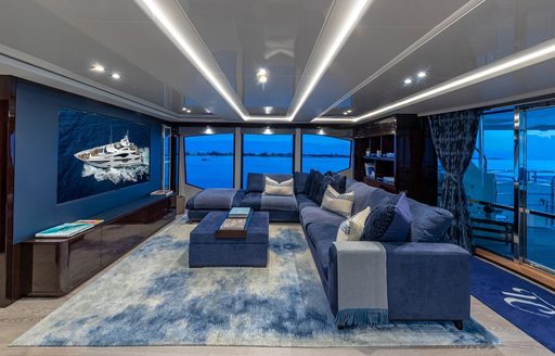 Upper salon with blue chairs and large screen onboard charter yacht TC 