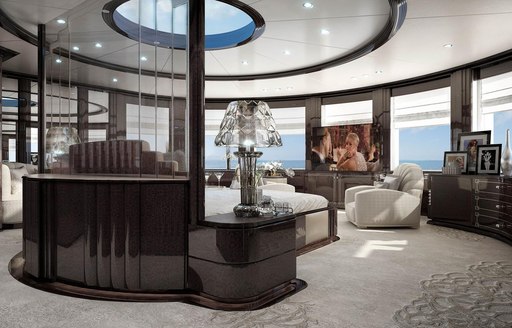 Charter yacht SPECTRE owners suite with grey carpets, black bed frame, skylight and glass furnishings. Great Gatsby on TV screen